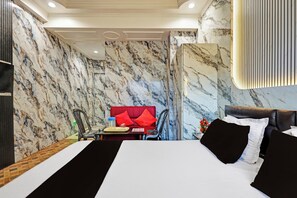 A hotel room with a bed, a red sofa, a dining table, and a wall with a marble pattern. - Collection Beach Formerly Bidisha (Digha)