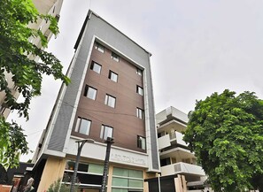 Un hotel de varios pisos con fachada moderna, balcones y un cartel que indica que es un hotel.