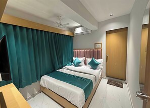 Habitación de hotel con cama, cortinas, ventilador de techo, equipo de aire acondicionado, puerta de madera y piso de mármol.