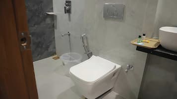 A modern bathroom with a toilet, a shower, and a sink.