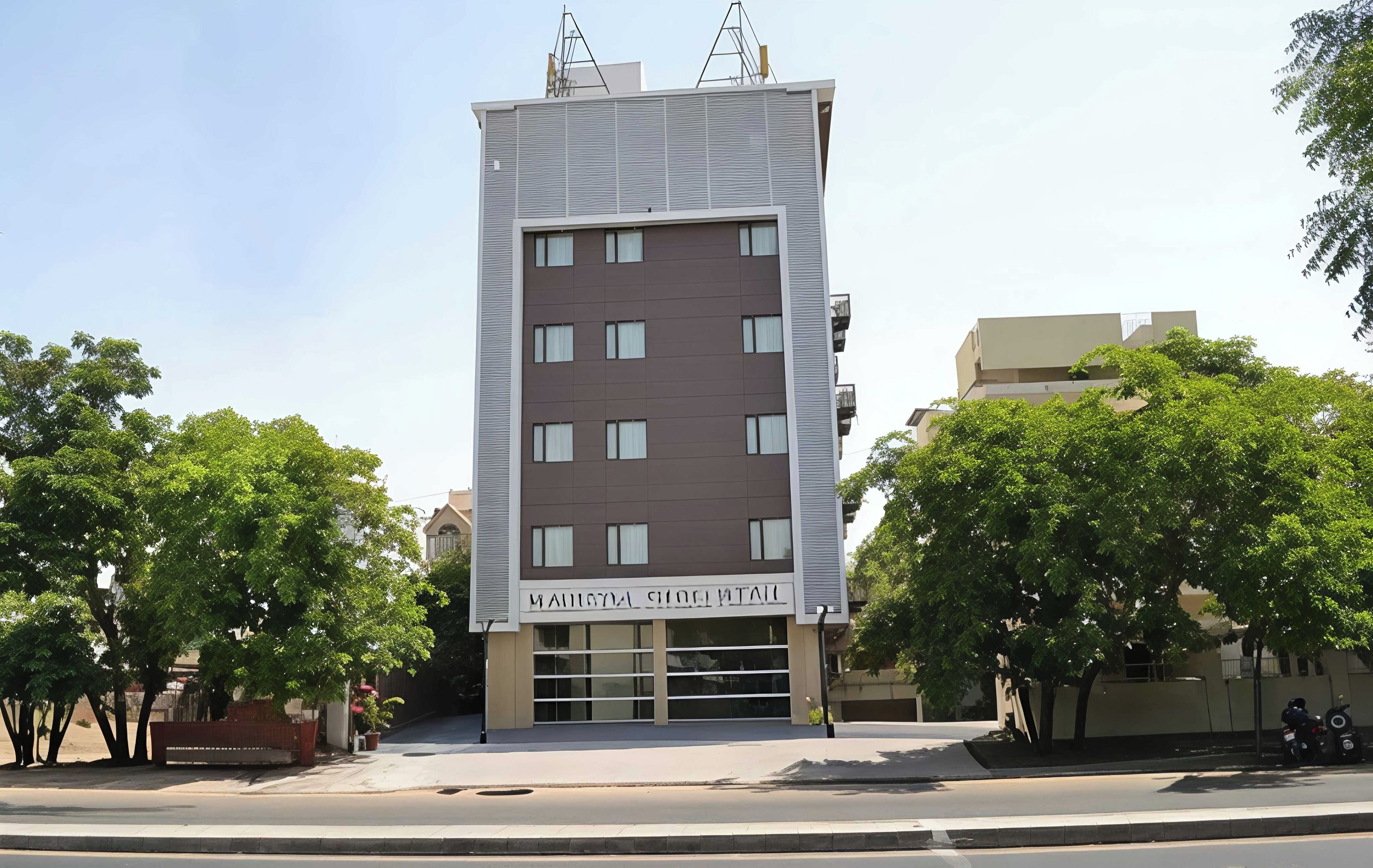 A modern multi-story building with a flat facade, large windows, and a sign indicating it is a hotel.