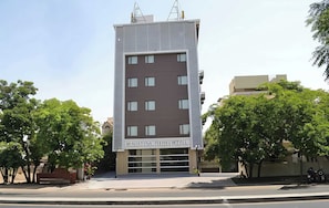 A modern multi-story building with a flat facade, large windows, and a sign indicating it is a hotel.