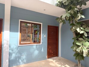 A building with a blue exterior, a wooden door, and a window with a view of a landscape. - La Parenthese El Nido (El Nido)