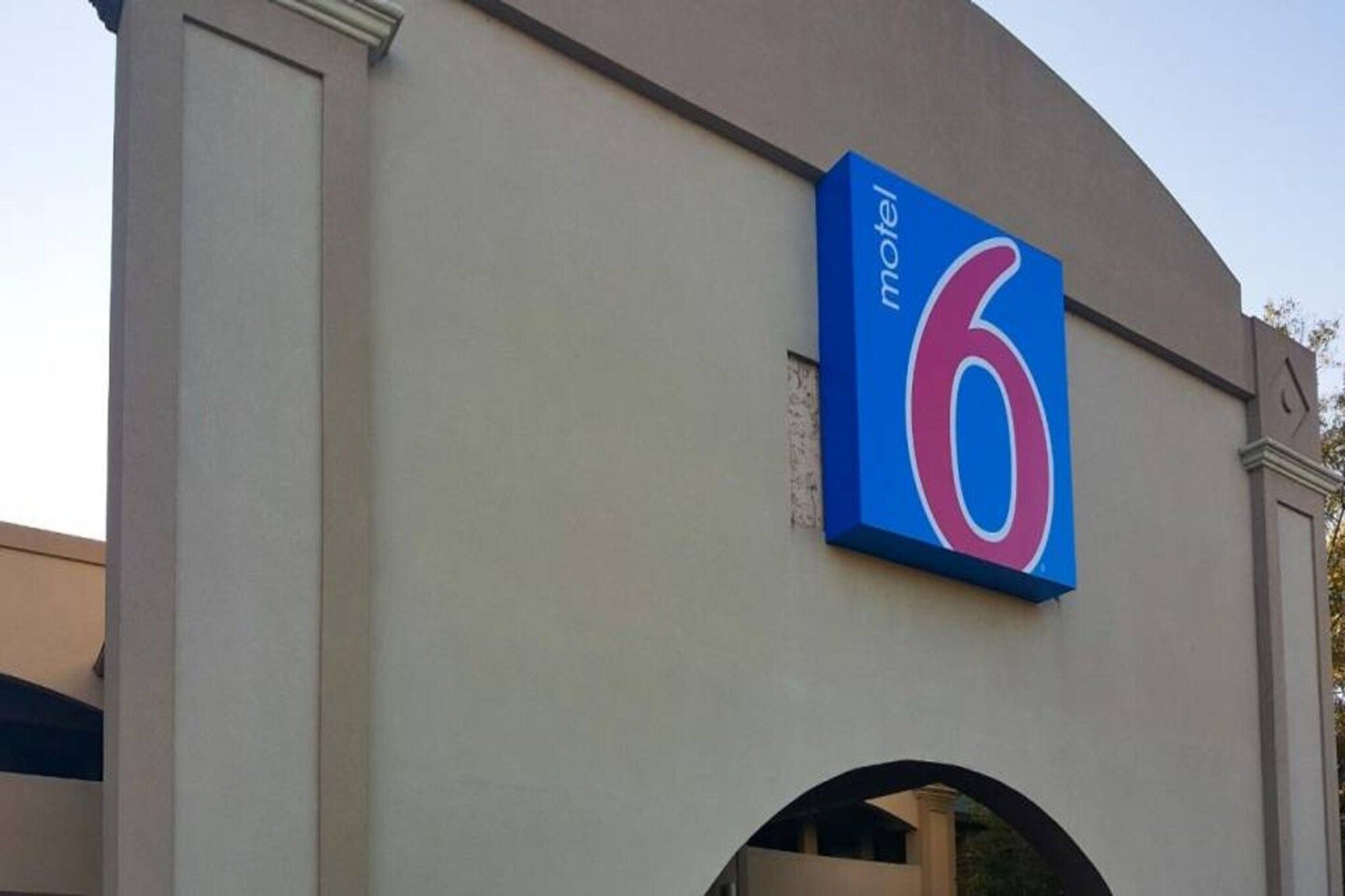 Un bâtiment avec une grande enseigne bleue portant le chiffre « 6 » et le mot « hôtel », indiquant qu’il s’agit d’un établissement hôtelier.