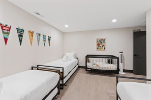 A hotel room with two single beds, a crib, a radiator, and a door. - New! Sapphire Collection Lake View Lodge, Hot Tub & Fire Pit! (Somers)