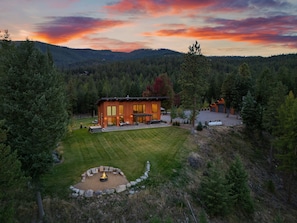 A modern house with a large deck, a fire pit, and a well-maintained lawn. - New! Sapphire Collection Lake View Lodge, Hot Tub & Fire Pit! (Somers)