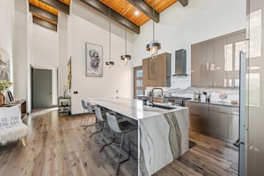 A modern kitchen with a large island, bar stools, pendant lighting, and a view of the outdoors. - New! Sapphire Collection Lake View Lodge, Hot Tub & Fire Pit! (Somers)