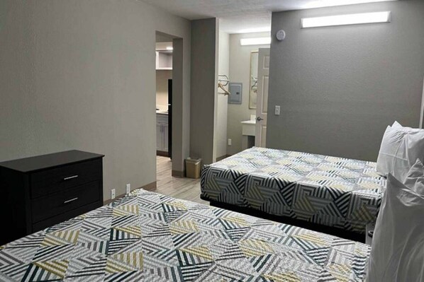 A bedroom with two beds, a dresser, and a bathroom visible in the background. - 2 Queen Beds|Non-Smoking (West Memphis)