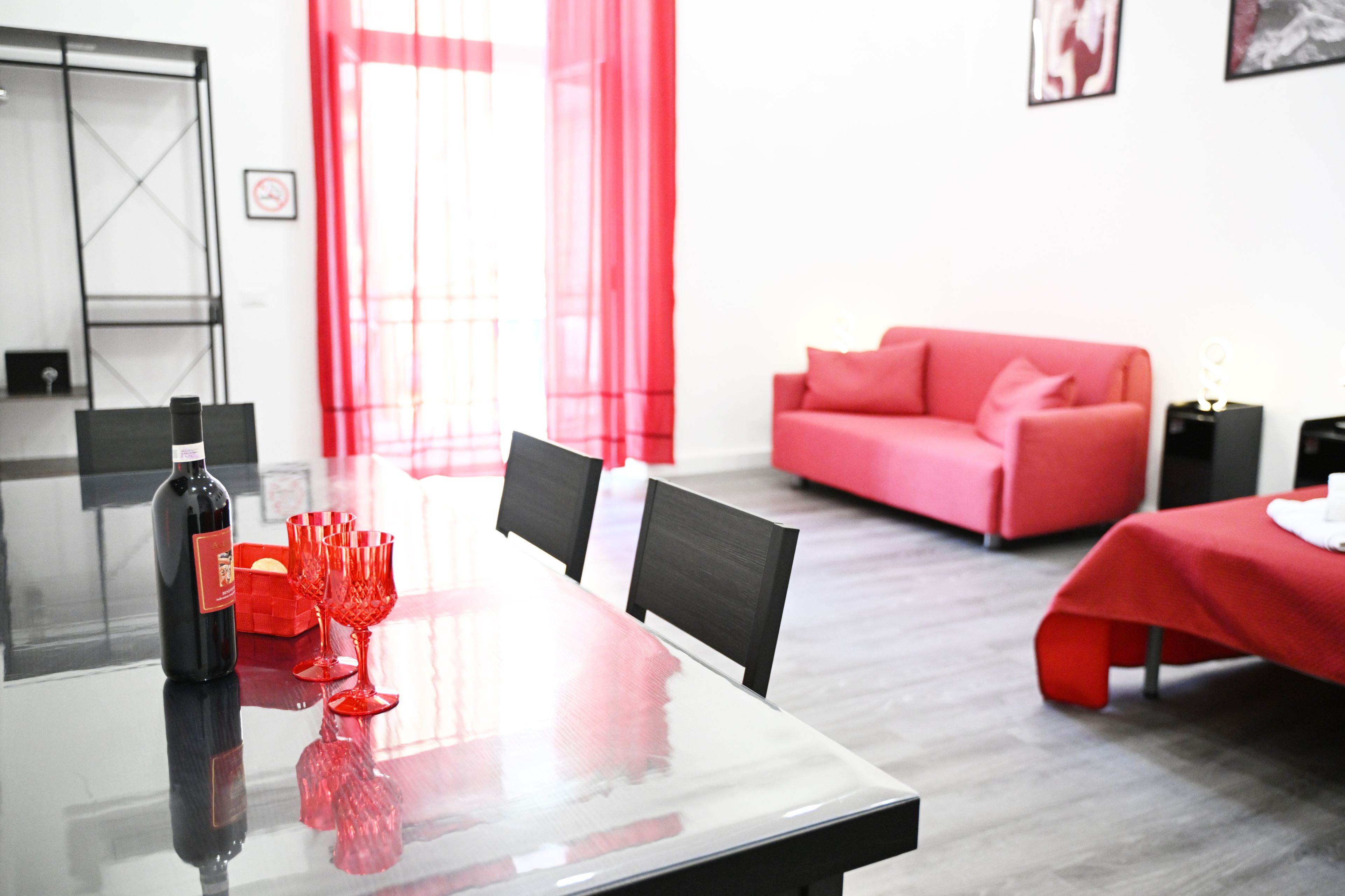 Habitación de hotel moderna con una mesa de comedor, sillas, un sofá y una cortina roja.