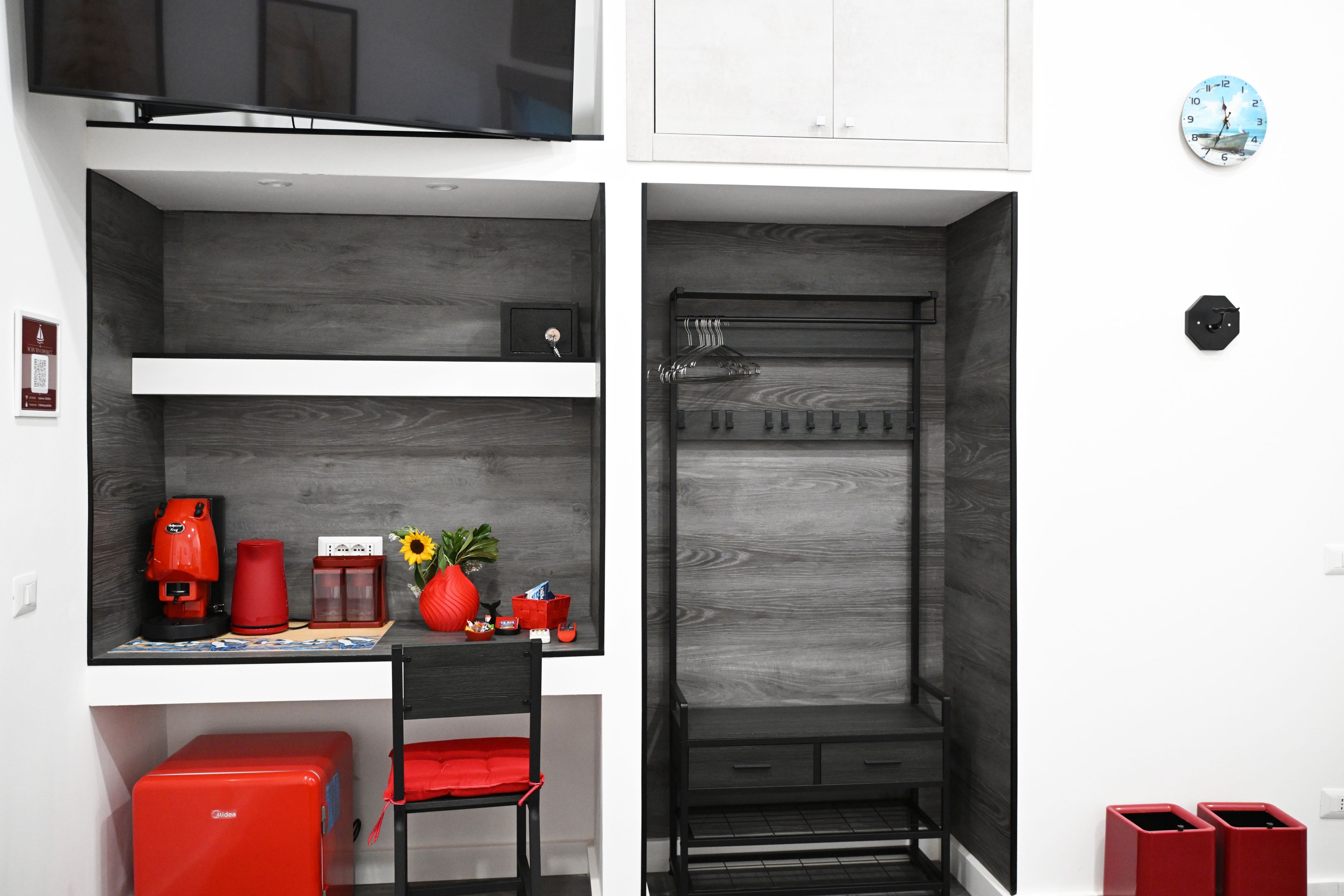 Uma cozinha compacta equipada com cafeteira, uma cadeira vermelha e uma mesa pequena.
