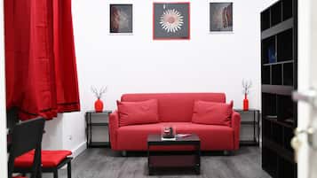 Ein rotes Sofa, ein schwarzer Couchtisch und ein roter Sessel in einem Zimmer mit weißer Wand und grauem Boden.