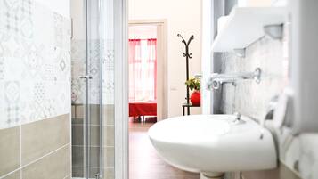 Un bagno con un lavandino bianco, box doccia in vetro e piastrelle decorate.