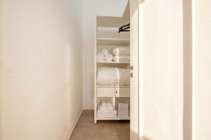 Ein begehbarer Kleiderschrank mit Regalen für gefaltete Handtücher und einer Kleiderstange.