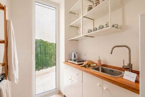 Une cuisine moderne dotée d’un four encastré, d’un évier et d’une fenêtre donnant sur un espace vert.