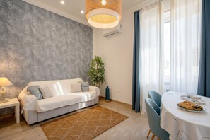 Ein modernes Wohnzimmer mit einer Couch, einem Esstisch und einer Pflanze.