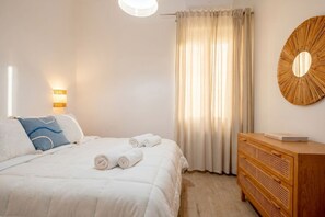 Ein Hotelzimmer mit einem Bett, einem Nachttisch, einer Wandlampe, einem Holzschrank und einem großen Spiegel.