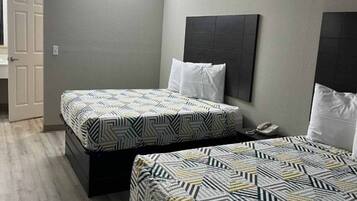 A hotel room with two beds, a bedside telephone, and a door to the left.