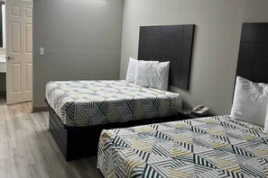 Ein Hotelzimmer mit zwei Betten, einem Nachttischtelefon und einer Tür links.