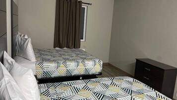 Une chambre à coucher avec un lit, une fenêtre avec des rideaux, une table de chevet et une armoire.