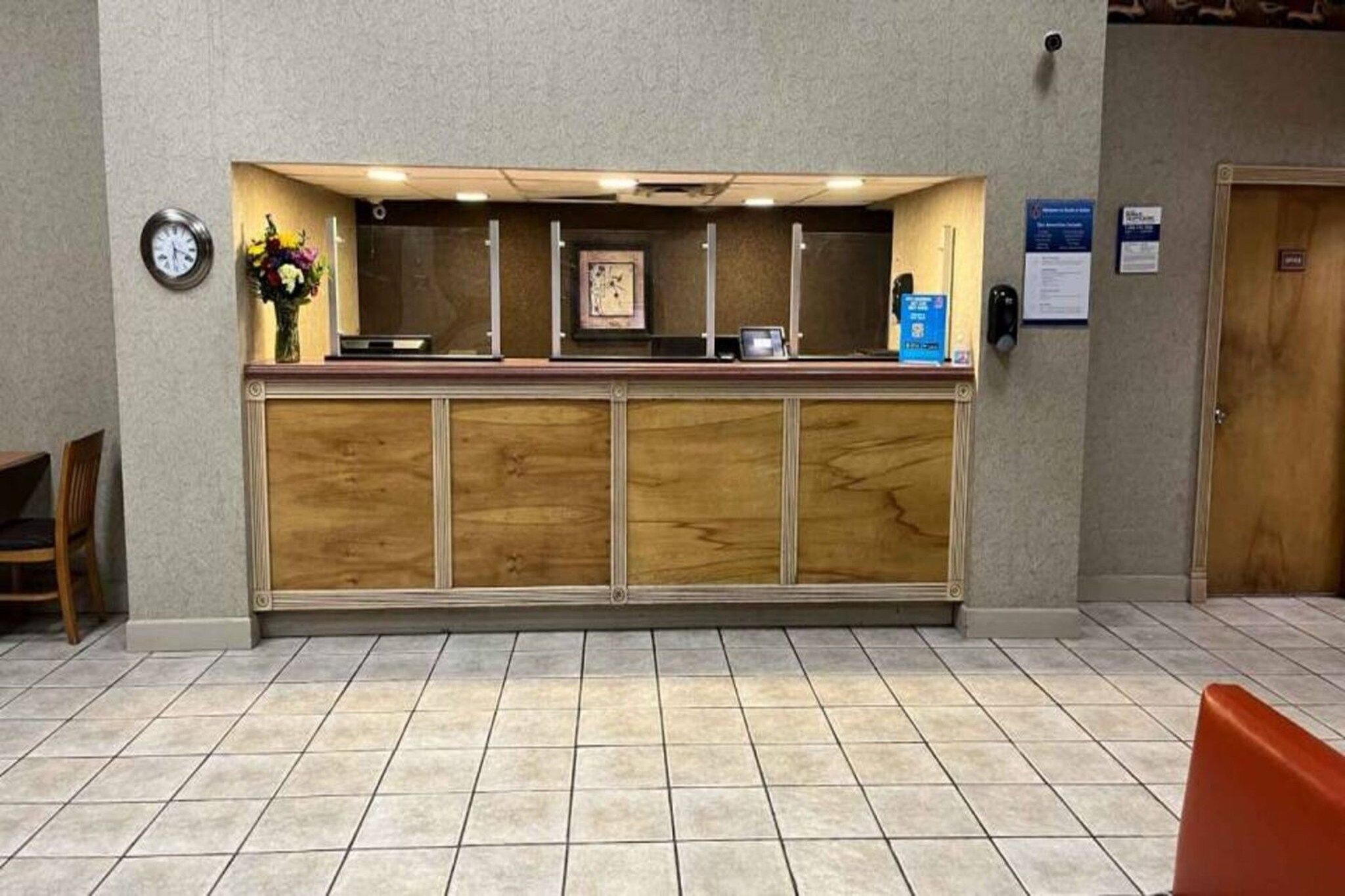 A reception desk with a clock, a framed picture, and a small plant on the counter.