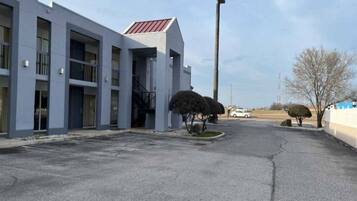 A modern building with a flat roof and a parking lot in front.