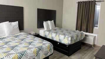 Quarto de hotel com duas camas, telefone de apoio, janela com cortinas e radiador.