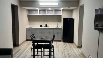 A compact kitchen with a dining table and chairs, a refrigerator, and a built-in oven.