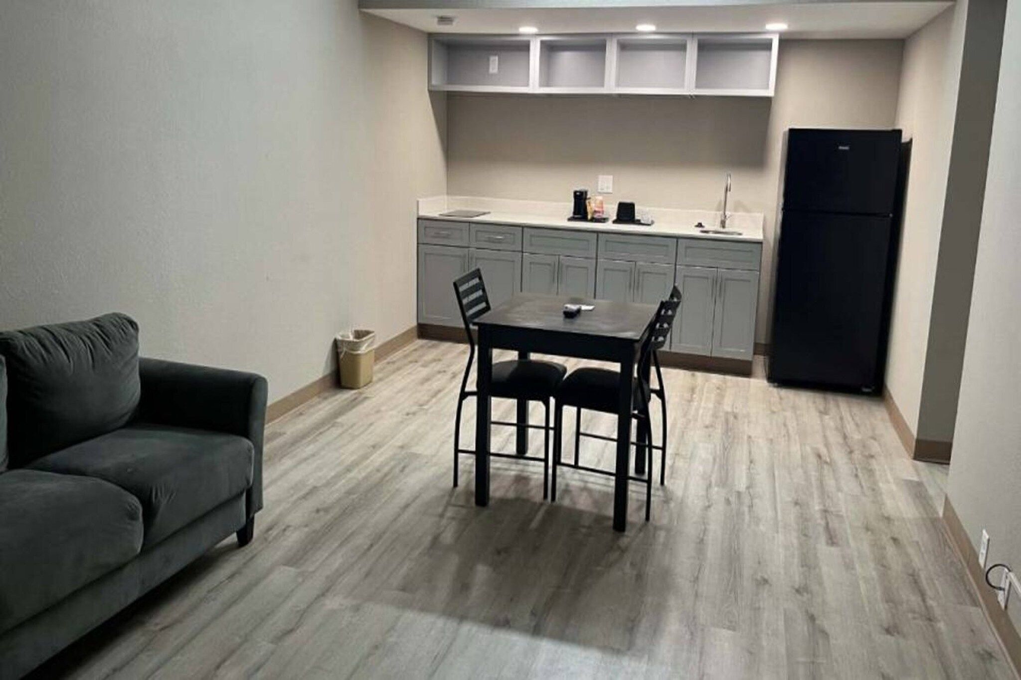 Un espace de vie compact comprenant une table et des chaises, un canapé, une kitchenette avec des placards et un réfrigérateur.