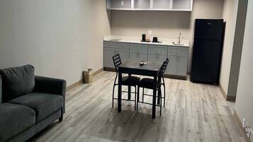 Un espace de vie compact comprenant une table et des chaises, un canapé, une kitchenette avec des placards et un réfrigérateur.