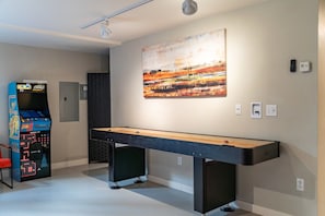 A room with a pool table, a pinball machine, and a large abstract painting on the wall. - Riverside Home | Walk Downtown | Hot Tub | Firepit (Winter Park)