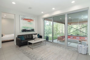 A modern living room with a sofa, coffee table, and a large abstract painting. - Riverside Home | Walk Downtown | Hot Tub | Firepit (Winter Park)