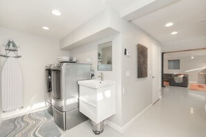 A modern kitchen with a built-in refrigerator, a white sink, and a glass door leading to a living area.