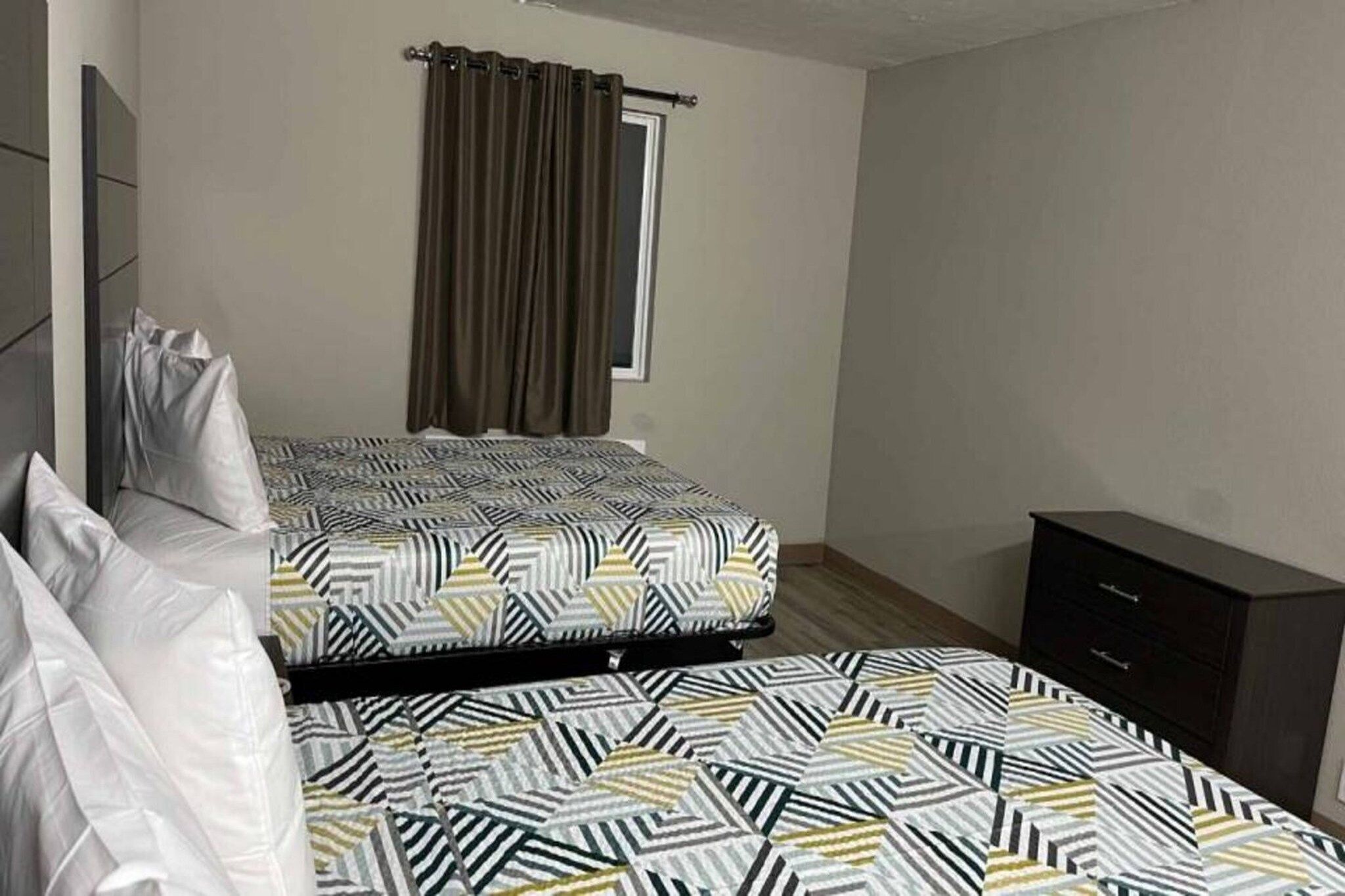 A bedroom with a bed, a window with curtains, a bedside table, and a wardrobe.