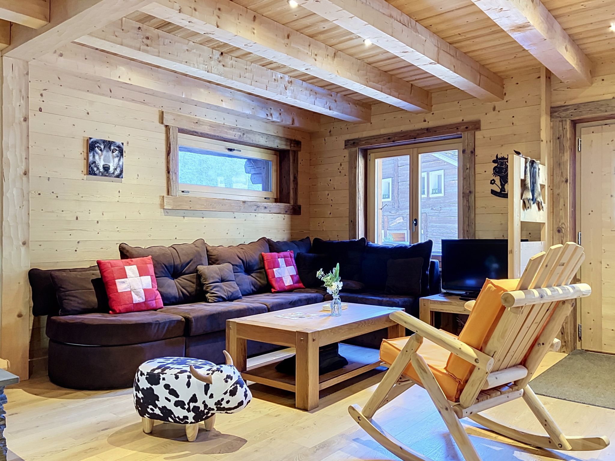 Ein gemütliches Blockhaus-Interieur mit einer Couch, einem Schaukelstuhl, einem Fernseher und einem Fenster mit Blick.