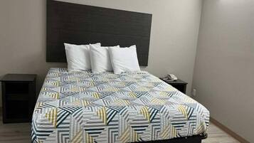 Ein Bett mit einem gemusterten Überwurf, zwei Nachttische und ein Kopfteil.