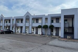 A row of modern, multi-story buildings with a uniform architectural style, featuring balconies and a flat roof.