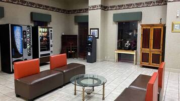 Eine Lobby mit einem braunen Sofa, einem Glastisch, Verkaufsautomaten und einer Holzkassette.