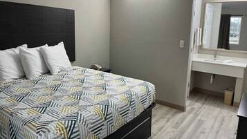 Une chambre à coucher comprenant un lit, une table de chevet, un miroir et une salle de bain avec un lavabo et des toilettes.