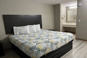 Una cama con una colcha estampada, un cabecero oscuro y una mesita de noche.