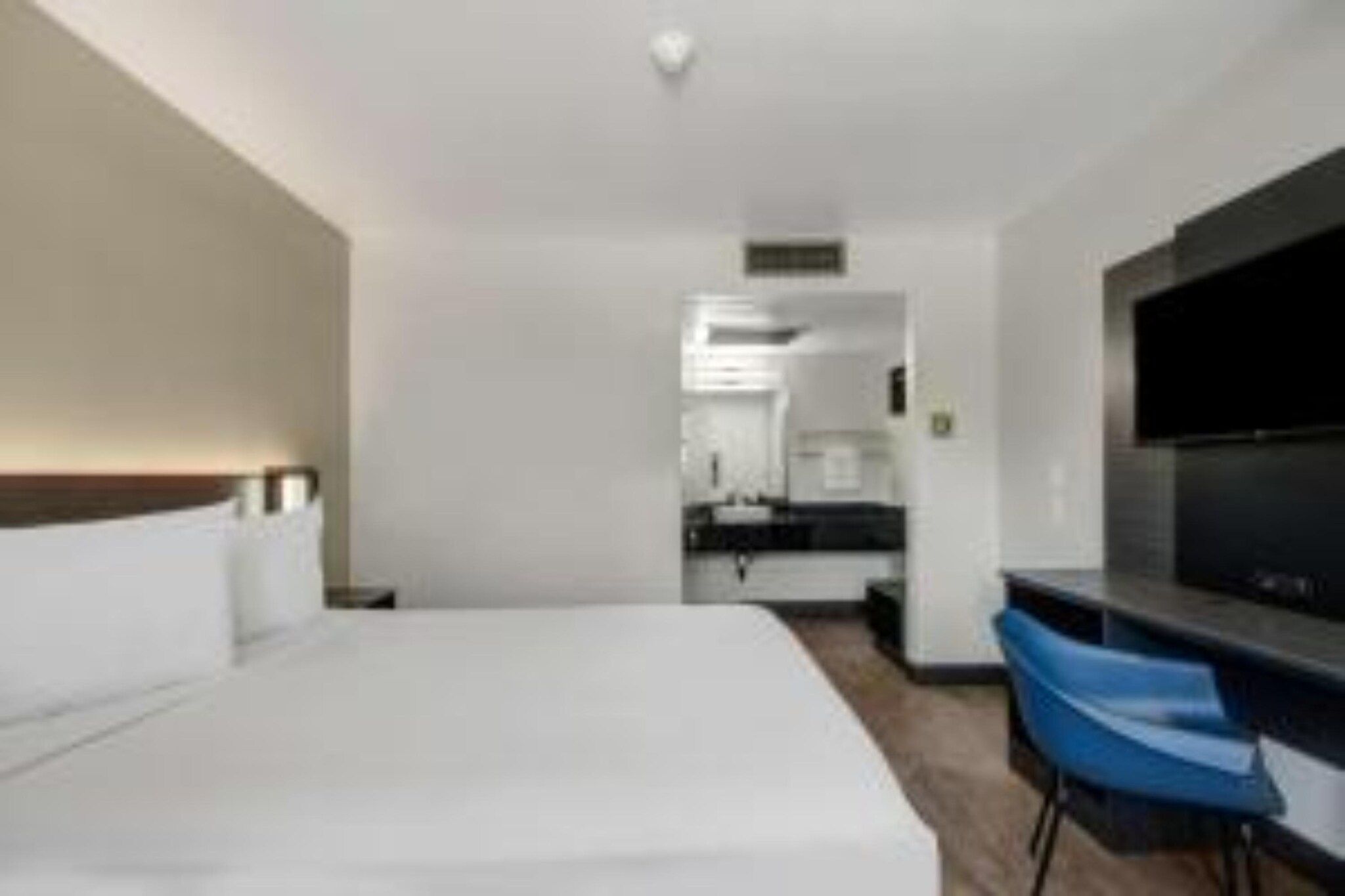 A hotel room with a bed, a desk, and a television.