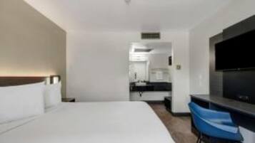 A hotel room with a bed, a desk, and a television.