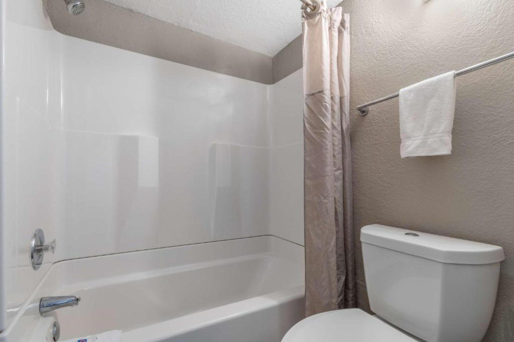 A bathroom with a bathtub, toilet, and shower curtain.