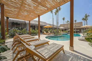 A poolside area with lounge chairs, umbrellas, and a pool.