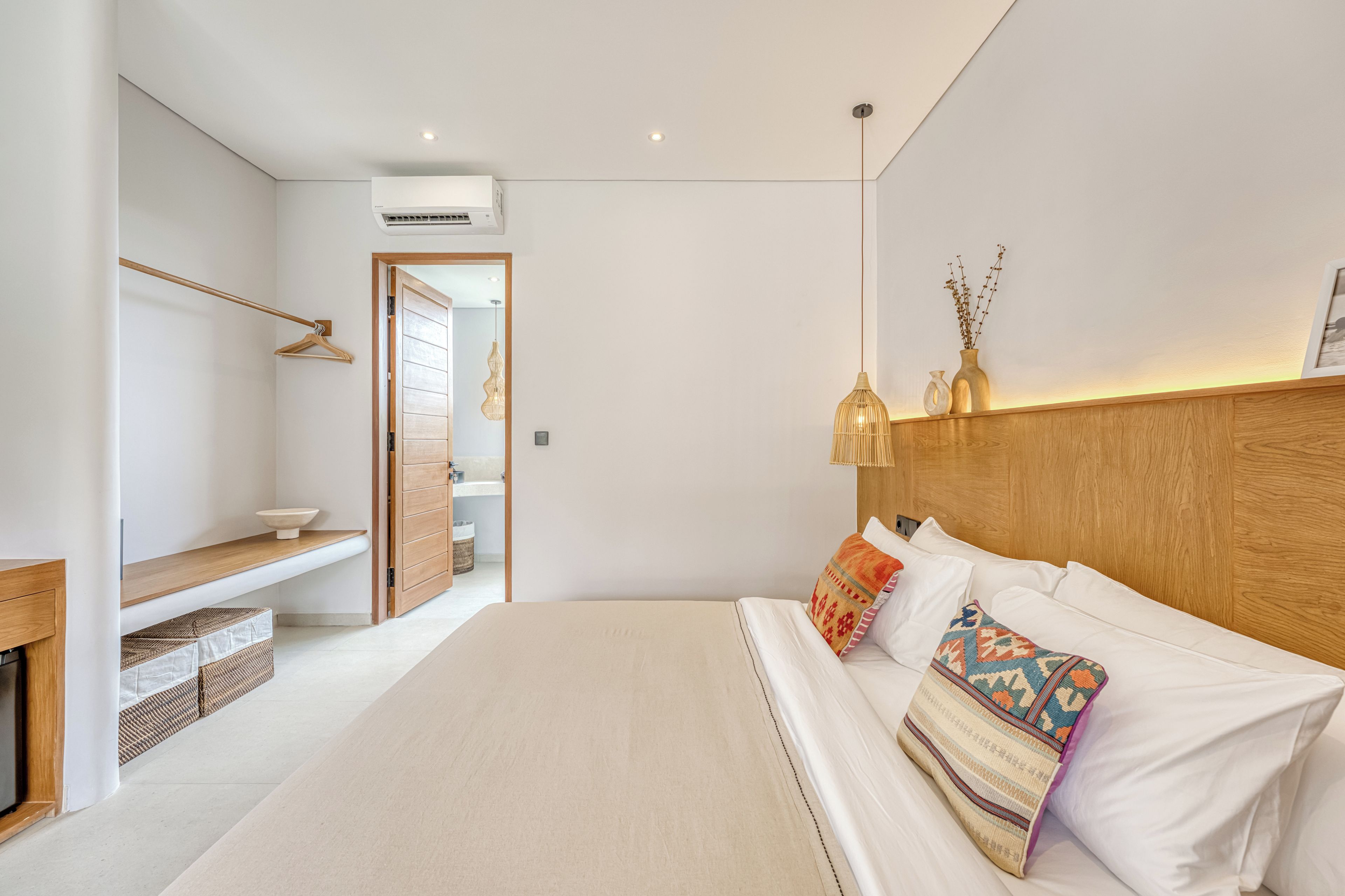 Un dormitorio moderno con una cama grande, cabecera de madera y una mesita de noche.