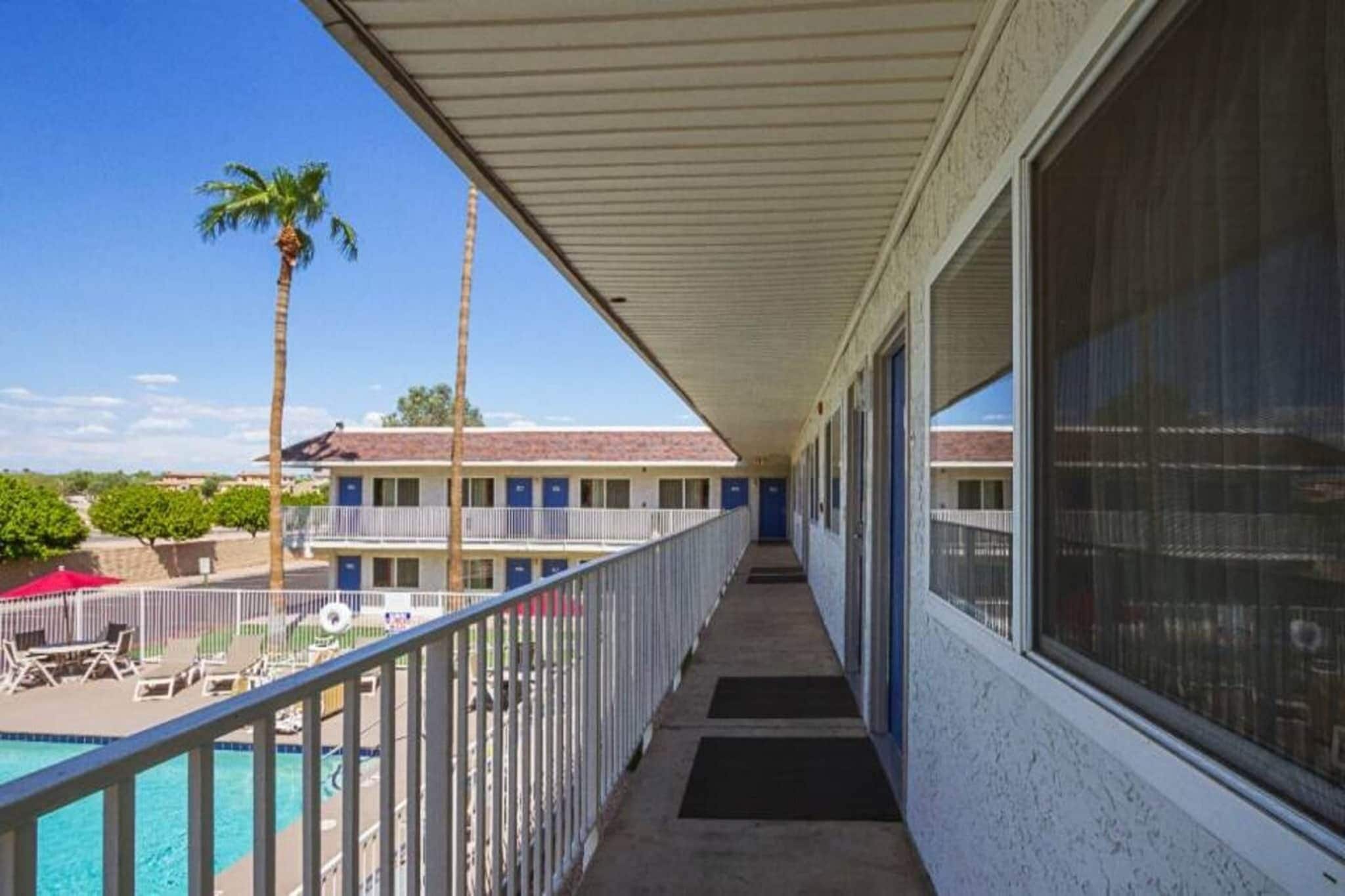 A hotel corridor with a pool, palm trees, and a view of the building.
