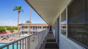 A hotel corridor with a pool, palm trees, and a view of the building.