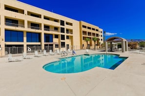 Ein Hotel mit Pool, Sitzgelegenheiten im Freien und Bergblick.