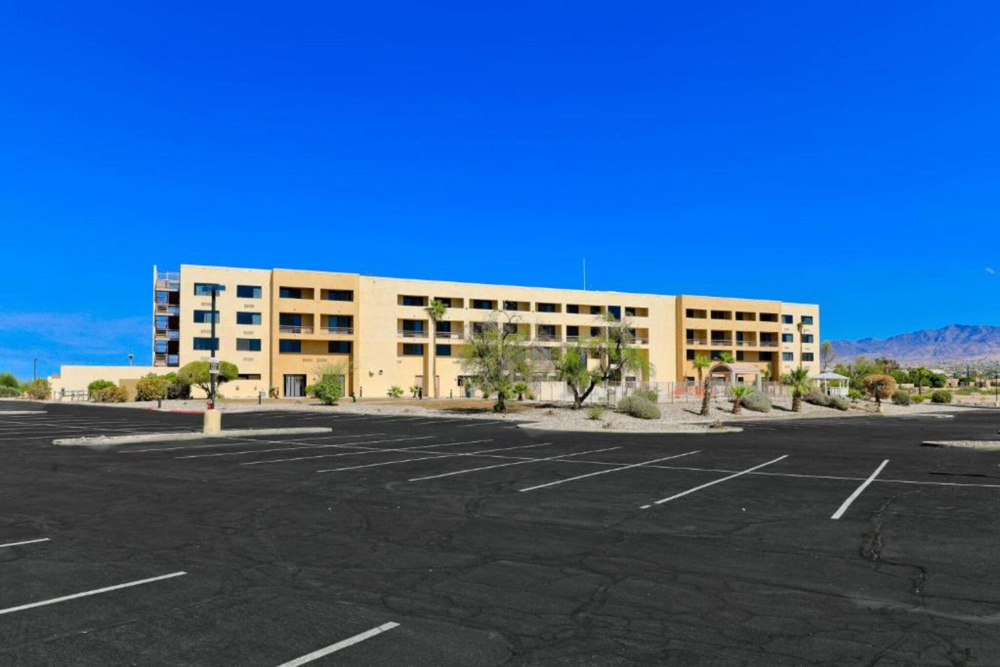 A multi-story hotel with a parking lot in front.