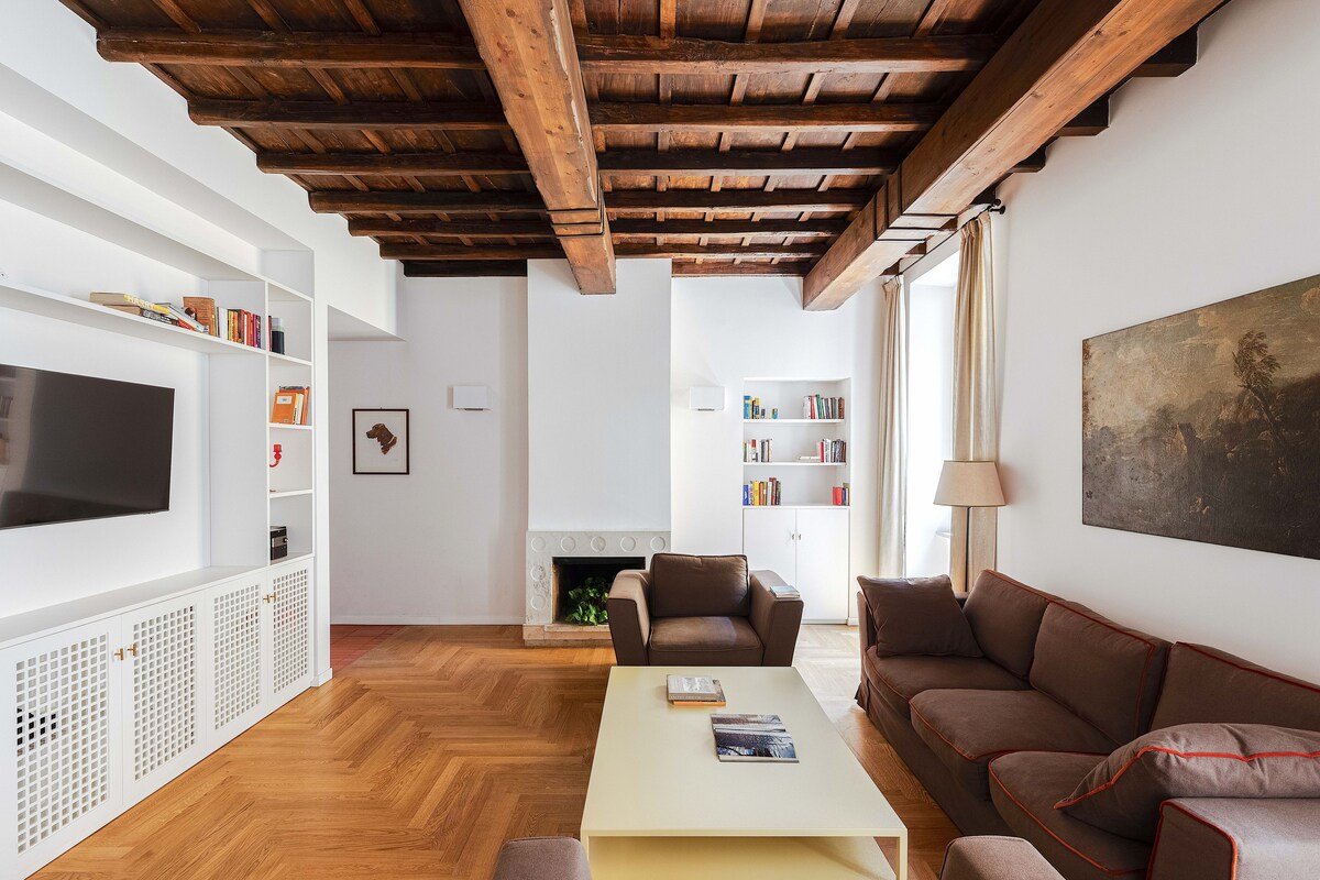 Ein Wohnzimmer mit Kamin, Fernseher und Bücherregalen.