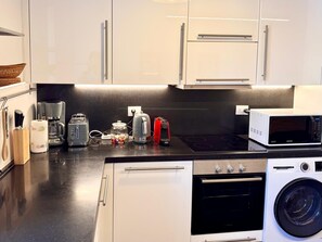 Eine moderne Küche mit Edelstahlgeräten, darunter eine Kaffeemaschine, ein Toaster, ein Wasserkocher und eine Mikrowelle.